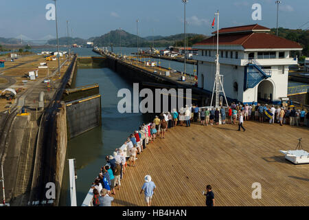 Passengers on a cruise ship line the rails as the ship enters the Miraflores Lock from the Pacific Ocean Stock Photo