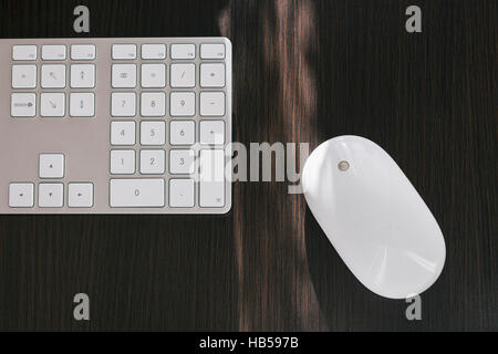 Apple mighty mouse on the dark desk next to the white keyboard Stock Photo
