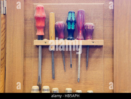 several screwdrivers hanging on wooden wall at workshop Stock Photo