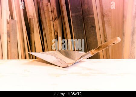 small old shovel on table in front of pile of wood Stock Photo