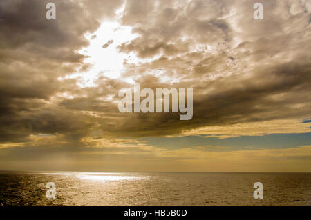 Sun breaking through clouds at sea. Stock Photo