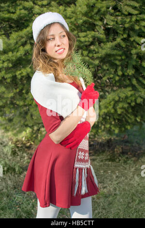 Beautiful Santa Claus girl with a fir tree branch outdoors Stock Photo