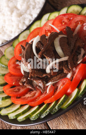 Cambodian cuisine: Beef Lok Lak with fresh vegetables close-up on a plate. vertical Stock Photo