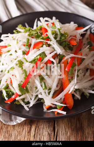 diet food: salad of daikon with pepper and herbs closeup on a plate. vertical Stock Photo