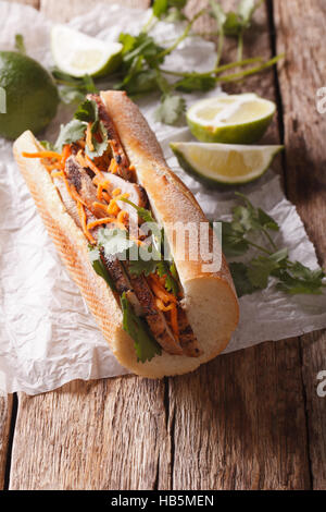 Traditional Vietnamese Banh Mi sandwich with pork, cilantro, carrot close-up on the table. vertical Stock Photo