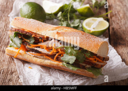 Vietnamese Pork Banh Mi Sandwich with Cilantro and carrot close-up on the table. Horizontal