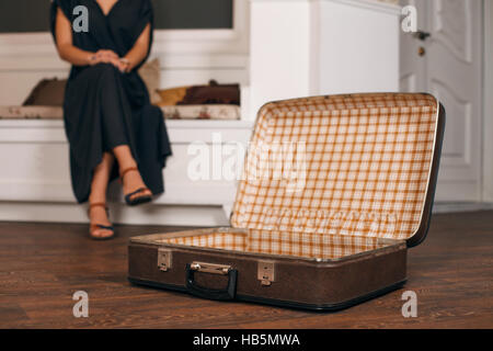 Woman sitting in front of an open suitcase . Stock Photo