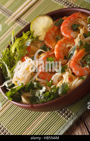 Malaysian laksa soup with prawns close up in a bowl on the table. Vertical Stock Photo