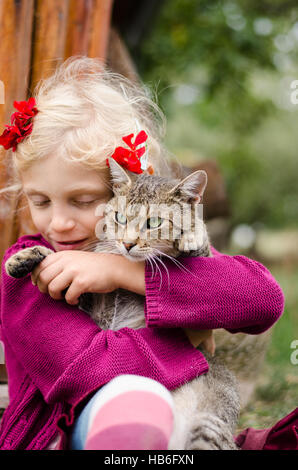 adorable caucasian blond girl holding domestic cat Stock Photo