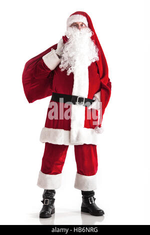 Santa Claus carrying big bag of gifts isolated on white background Stock Photo