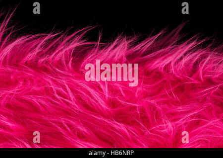 Pink plush fabric on black background horizontal. Very soft polyester textile made of synthetic fibers with long hairs. Macro. Stock Photo
