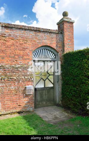 Wooden garden gate with red wall Stock Photo