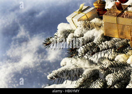 Christmas background.Branch of fir-tree is covered with snow . Gift boxes and decoration . Stock Photo