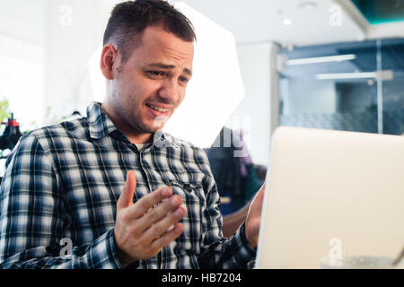 Worried shoked man looking on laptop at cafe Stock Photo