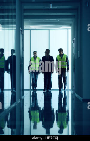 Several businesspeople and workers walking in dark corridor Stock Photo