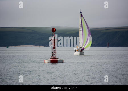 Classic yacht with cruising chute approaches the Qatar buoy in Milford Haven, with Watwick beach in the background Stock Photo