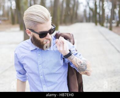 Blond hipster guy in shirt with tatoo on arms representing youth culture. Stock Photo
