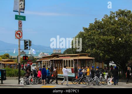 San Francisco, California - Mai 23, 2015: Tourists riding on the iconic cable car, blue sky day at top of Hyde Street view overlooking the bay water a Stock Photo