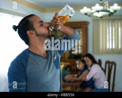 Social issues, abuse and aggression on women, alcoholic latino man and sad woman crying at home. Violent husband and abused wife with child Stock Photo