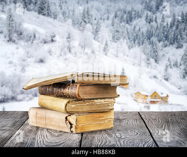 Old books on the wooden table against the background bokeh winter mountains Stock Photo