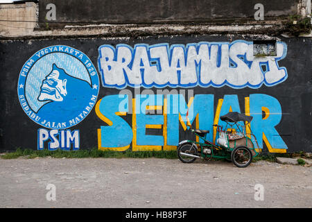 Street art in Yogyakarta with a parked ojek. The street art in Yogyakarta often has a political message. Java, Indonesia. Stock Photo