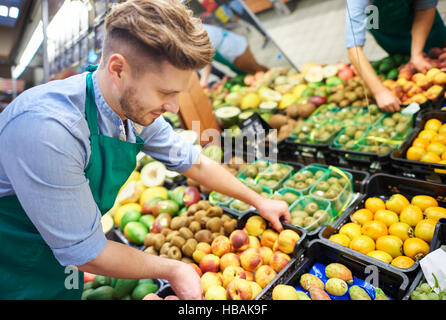 Sales clerk grabbing the box of fruits Stock Photo