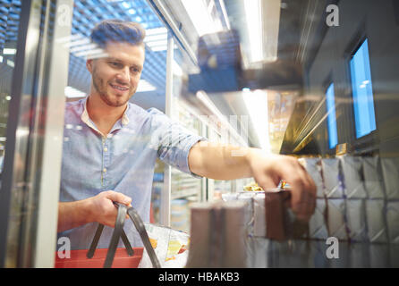 Man shopping for groceries in supermarket freezer Stock Photo