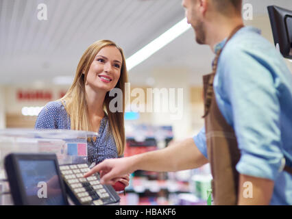 Woman next to cash register talking with sales clerk Stock Photo