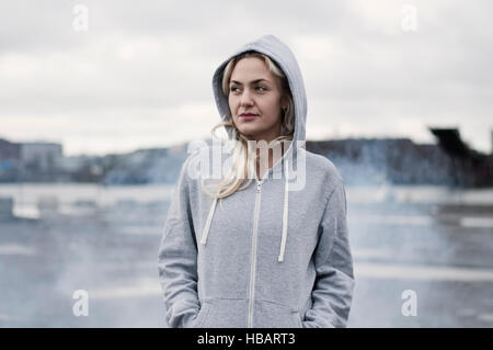 Portrait of female runner in hoody on stormy dockside Stock Photo