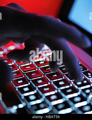 A dark mystery hand typing on a laptop computer at night Stock Photo