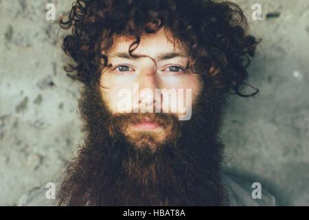 Close up portrait of young male hipster with brown curly hair and beard Stock Photo