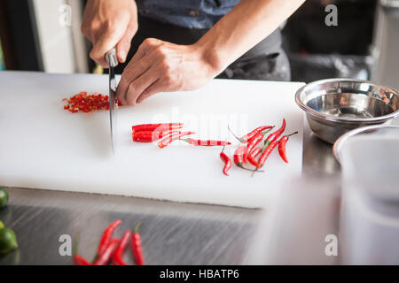 Cropped view of man slicing red chilli peppers Stock Photo