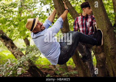 Portrait of father and son, fooling around, hanging in tree Stock Photo