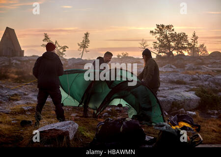 Hikers setting up tent at sunset, Sarkitunturi, Lapland, Finland Stock Photo