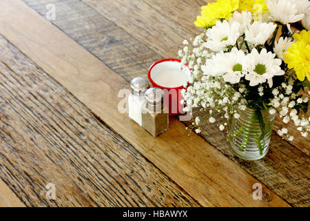 Wooden table in coffee shop with flower arrangement and salt & pepper Stock Photo