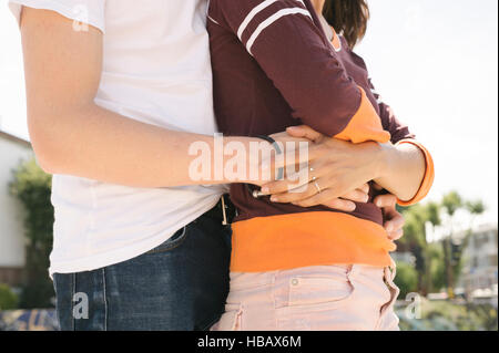 Mid section of young man with arms around girlfriend in city skatepark Stock Photo