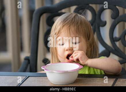 Small baby girl eating from bowl Stock Photo