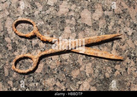 Old rusty scissors on a granite countertop. Old tool tailor. Stock Photo
