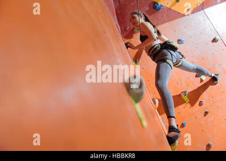 Slim young woman training hard in climbing gym Stock Photo