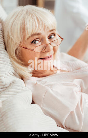 Pleasant delighted aged woman lying in bed Stock Photo