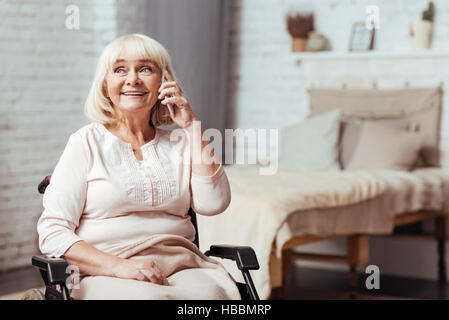 Cheerful disabled senior woman talkign on smart phone Stock Photo