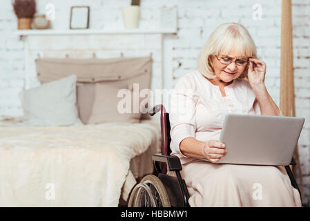 Nice disabled aged woman using laptop Stock Photo