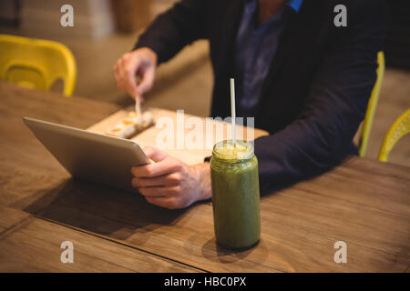 Businessman using digital tablet while having snacks Stock Photo
