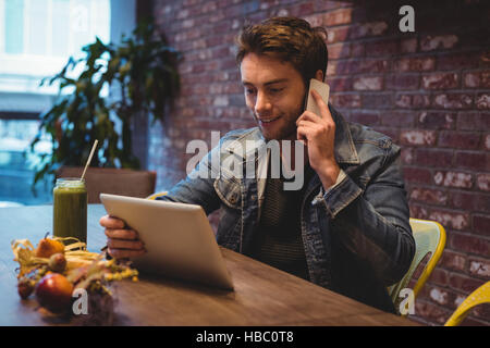 Man talking on mobile phone while using digital tablet Stock Photo