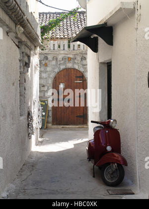Red Vespa scooter in alley way outside Skouna nightclub in Roda Corfu Greece Stock Photo