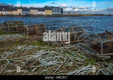 Fishing nets and  lobster cages on Claddagh in Galway. Colorful houses in the background. Stock Photo