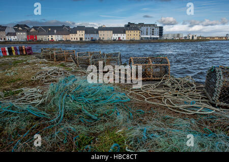 Fishing nets and  lobster cages on Claddagh in Galway. Colorful houses in the background. Stock Photo