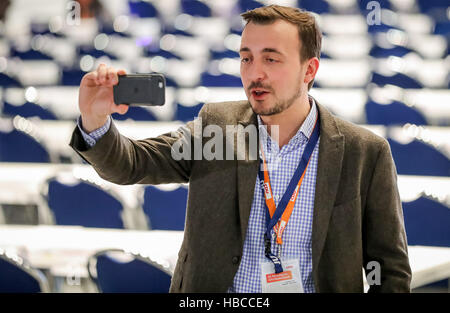 Essen, Germany. 5th Dec, 2016. Paul Ziemiak, Chairman of the CDU youth organisation 'Junge Union', holds up his smartphone during a visit to the Gruga hall before the CDU Federal Party Conference in Essen, Germany, 5 December 2016. The party conference will last until 7 December 2016. Photo: Michael Kappeler/dpa/Alamy Live News Stock Photo