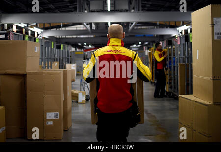 A DHL worker carries packages in Berlin, Germany, 06 December 2016. The German company's busy Christmas period is already in full swing. Photo: Britta Pedersen/dpa-Zentralbild/dpa Stock Photo