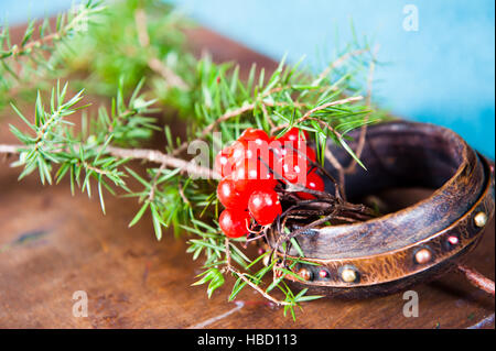 Winter scene with fresh green branches of pine, holly, juniper, cones, star, red berries barberry in natural wooden planter on bark weathered background, outdoors and space, daylight Stock Photo